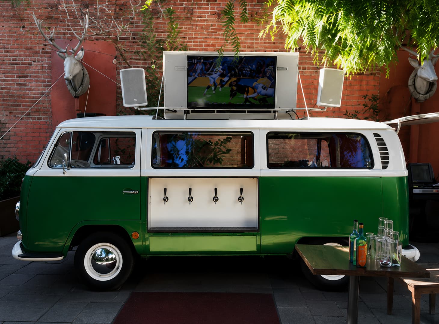 Green VW T2 beer truck with large TV screen on roof and speakers for sports events